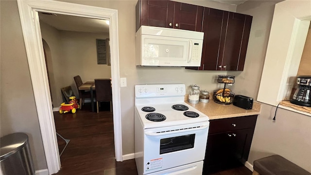 kitchen with dark brown cabinets, dark wood-type flooring, and white appliances