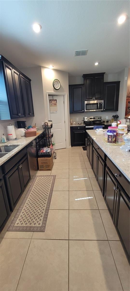 kitchen featuring stainless steel appliances, sink, light stone counters, and light tile patterned floors