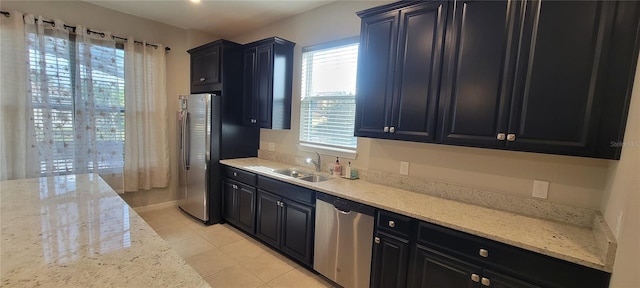 kitchen with appliances with stainless steel finishes, light stone countertops, sink, and light tile patterned floors