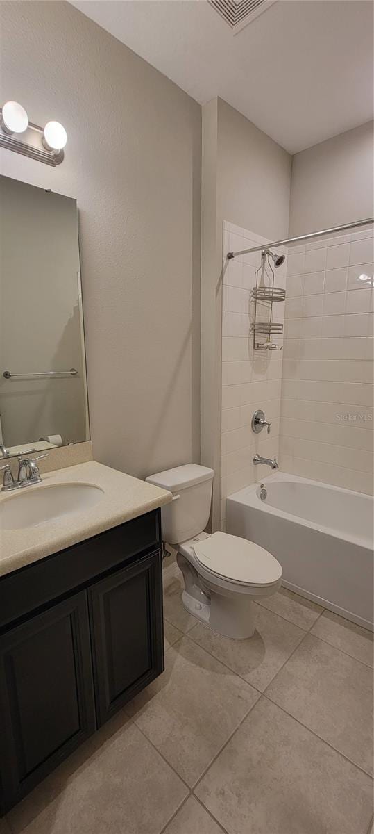 full bathroom featuring vanity, tiled shower / bath combo, tile patterned floors, and toilet