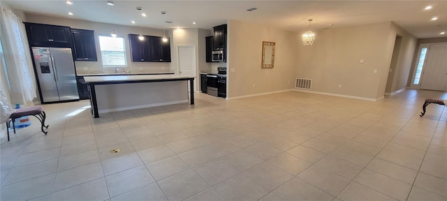 kitchen with a chandelier, hanging light fixtures, light tile patterned floors, appliances with stainless steel finishes, and a kitchen island