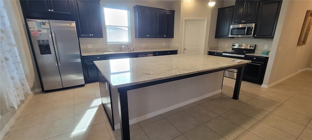 kitchen featuring sink, light stone counters, a center island, light tile patterned floors, and appliances with stainless steel finishes