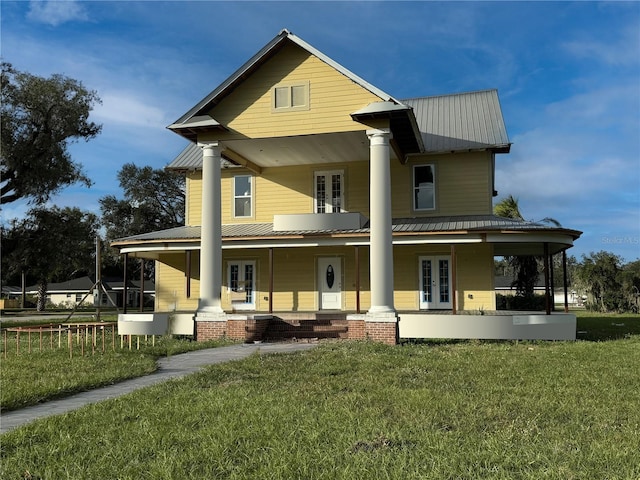 rear view of property with french doors, covered porch, and a lawn