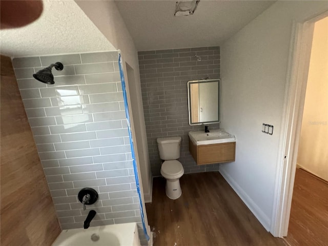 full bathroom featuring wood-type flooring, vanity,  shower combination, toilet, and a textured ceiling