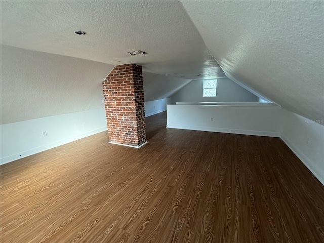 bonus room with lofted ceiling, hardwood / wood-style flooring, and a textured ceiling