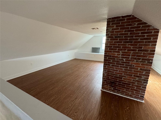 additional living space with lofted ceiling, dark hardwood / wood-style floors, and a textured ceiling