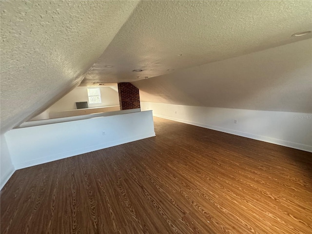 bonus room with wood-type flooring, a textured ceiling, and vaulted ceiling