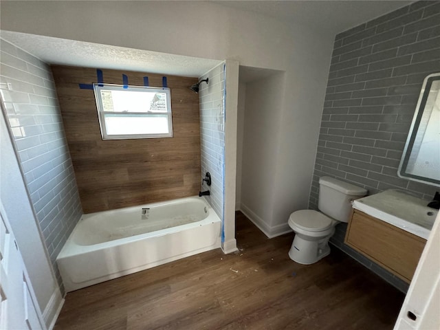 full bathroom with shower / washtub combination, hardwood / wood-style floors, tile walls, vanity, and toilet