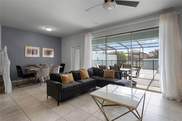 living room with ceiling fan, light tile patterned flooring, and a textured ceiling