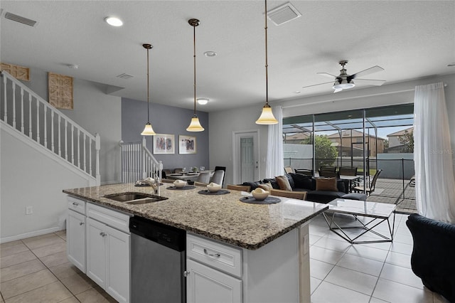 kitchen featuring light stone countertops, white cabinets, pendant lighting, dishwasher, and an island with sink