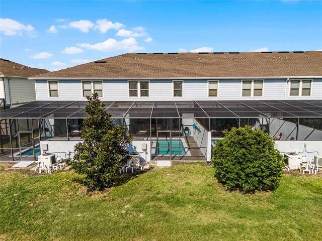 back of property with a lawn and glass enclosure