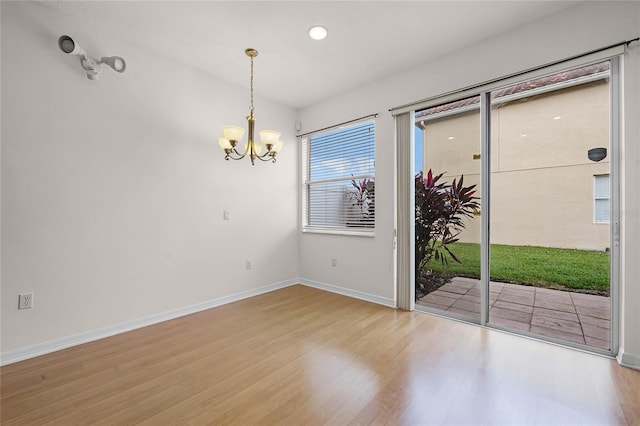 spare room with hardwood / wood-style floors and an inviting chandelier