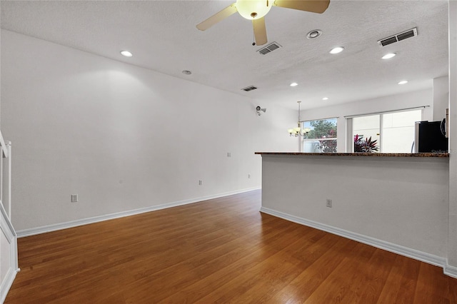 unfurnished living room with a textured ceiling, ceiling fan, and dark hardwood / wood-style floors