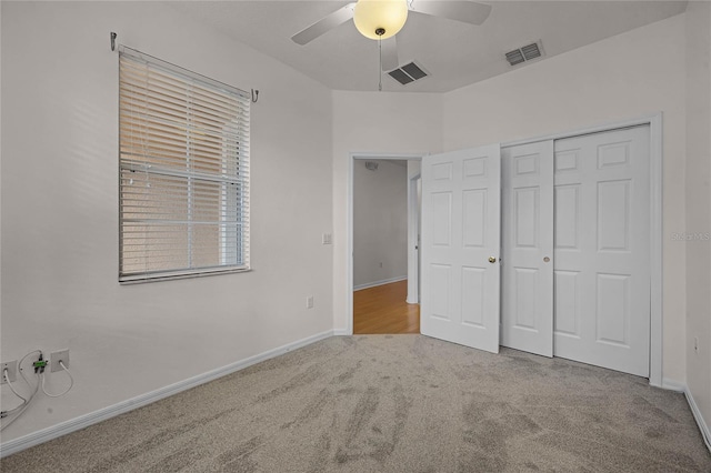 unfurnished bedroom featuring ceiling fan, a closet, and light colored carpet