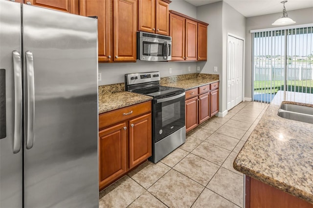 kitchen featuring light stone countertops, light tile patterned floors, stainless steel appliances, and decorative light fixtures