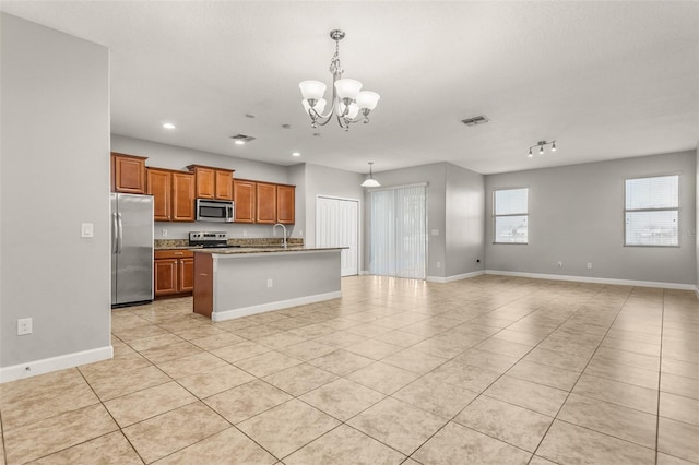 kitchen with appliances with stainless steel finishes, a kitchen island with sink, decorative light fixtures, a chandelier, and light tile patterned flooring