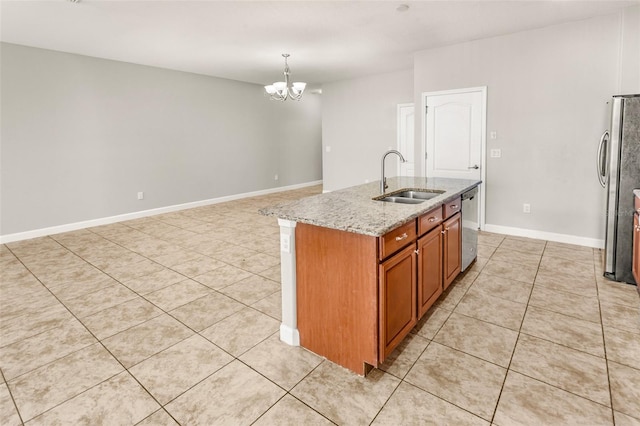 kitchen featuring light stone counters, stainless steel appliances, sink, a center island with sink, and a notable chandelier