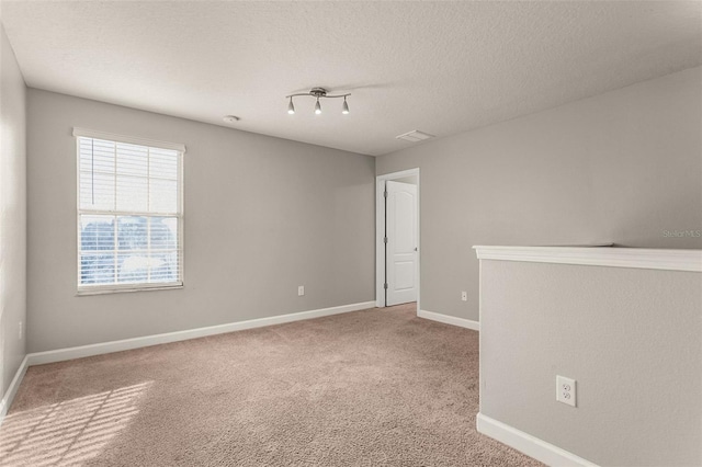 carpeted spare room with a textured ceiling