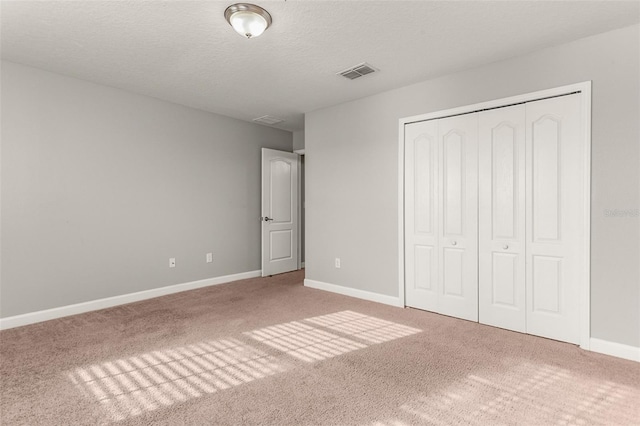 unfurnished bedroom featuring carpet flooring, a textured ceiling, and a closet