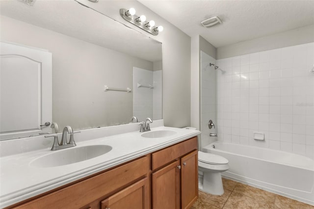 full bathroom featuring tile patterned floors, a textured ceiling, toilet, vanity, and tiled shower / bath