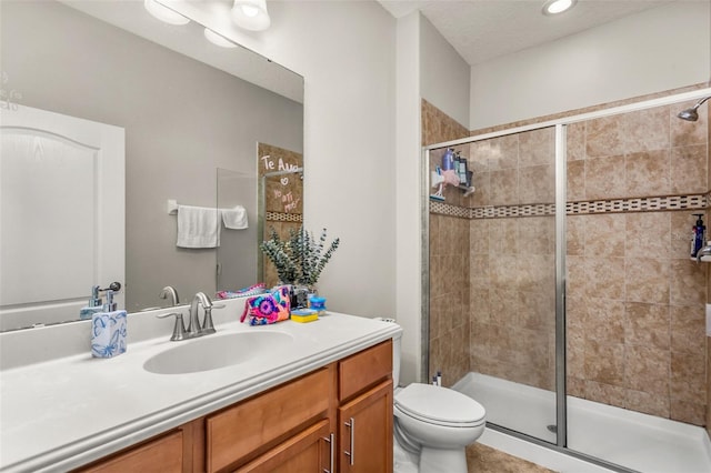 bathroom with vanity, toilet, an enclosed shower, and a textured ceiling