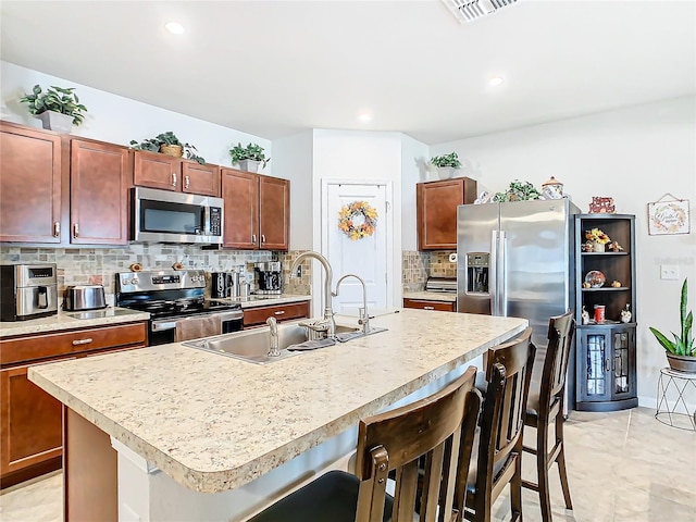 kitchen with sink, stainless steel appliances, and an island with sink