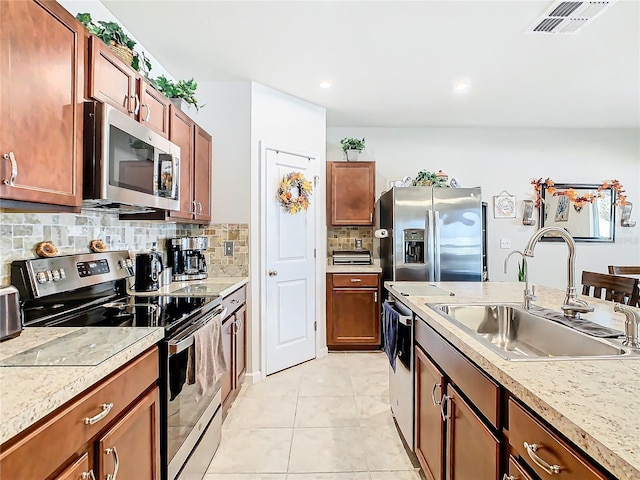 kitchen featuring backsplash, sink, light tile patterned floors, and stainless steel appliances