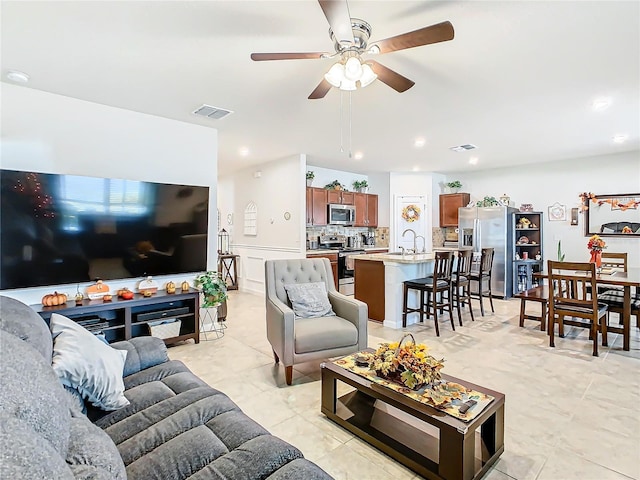 living room featuring light tile patterned floors, ceiling fan, and sink