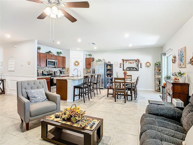 living room featuring light tile patterned floors, ceiling fan, and sink