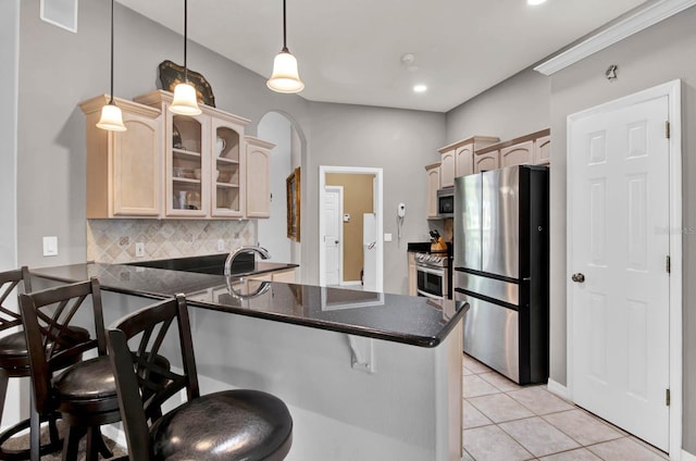 kitchen featuring stainless steel appliances, a breakfast bar, light brown cabinets, and kitchen peninsula