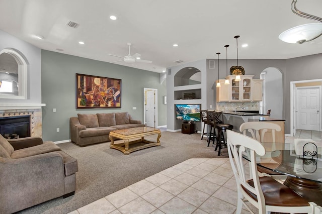 carpeted living room featuring ceiling fan, sink, and a fireplace