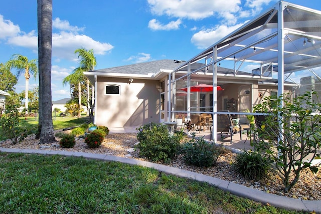 rear view of property with a patio, a yard, and glass enclosure