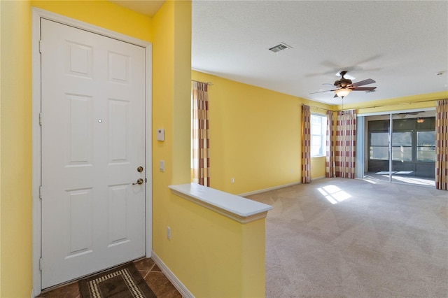 foyer with a textured ceiling, ceiling fan, and carpet floors