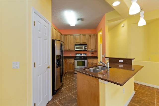 kitchen with stainless steel appliances, hanging light fixtures, a textured ceiling, sink, and dark tile patterned floors