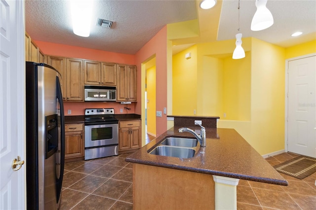 kitchen featuring sink, kitchen peninsula, appliances with stainless steel finishes, a textured ceiling, and hanging light fixtures