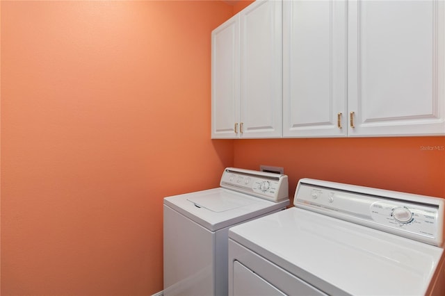 laundry area featuring separate washer and dryer and cabinets