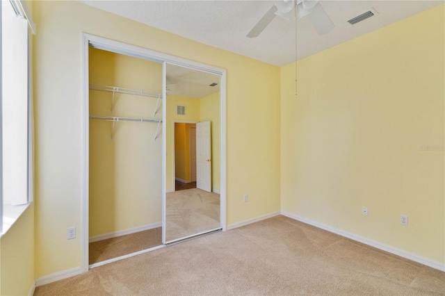 unfurnished bedroom with light colored carpet, ceiling fan, and a closet