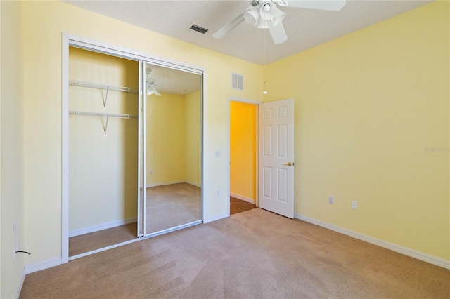 unfurnished bedroom featuring ceiling fan, a closet, and light colored carpet