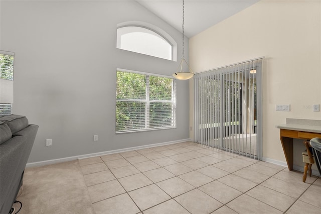 dining space with high vaulted ceiling and light tile patterned floors