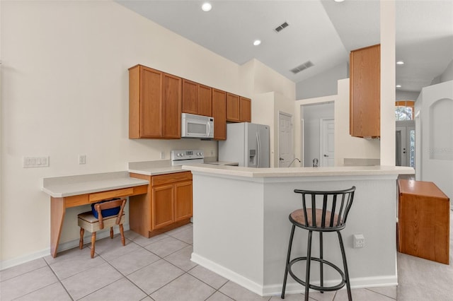 kitchen with kitchen peninsula, a kitchen breakfast bar, white appliances, light tile patterned floors, and lofted ceiling