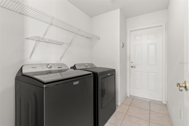 clothes washing area with light tile patterned floors and separate washer and dryer