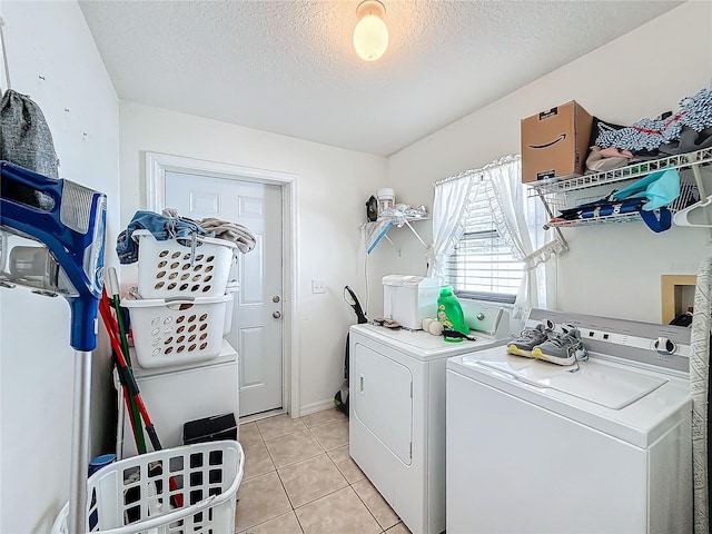 washroom featuring washer and clothes dryer, light tile patterned floors, and a textured ceiling