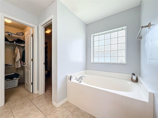 bathroom with tile patterned flooring, a textured ceiling, toilet, and a washtub