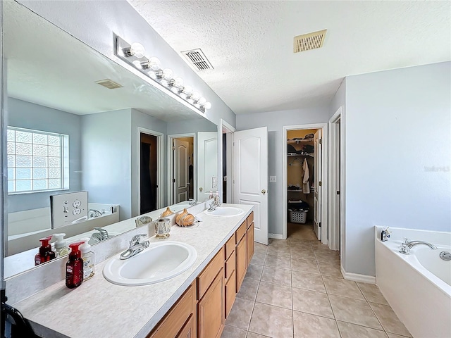 bathroom with tile patterned flooring, a textured ceiling, vanity, and a tub