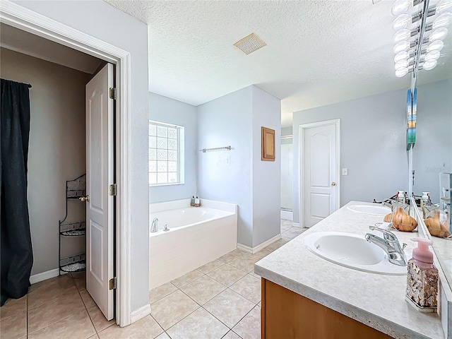 bathroom featuring tile patterned flooring, vanity, a bath, and a textured ceiling