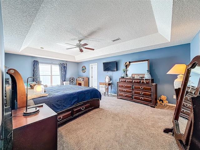 bedroom featuring carpet flooring, ceiling fan, a raised ceiling, and a textured ceiling