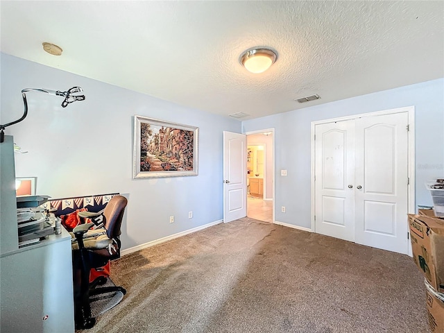 carpeted office space featuring a textured ceiling