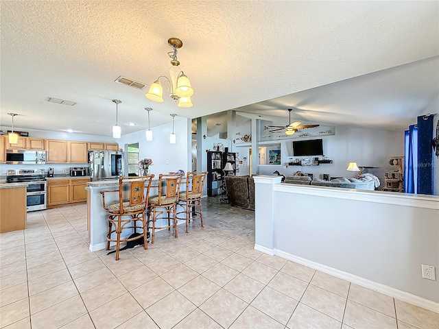 kitchen with a breakfast bar area, hanging light fixtures, stainless steel appliances, and ceiling fan with notable chandelier