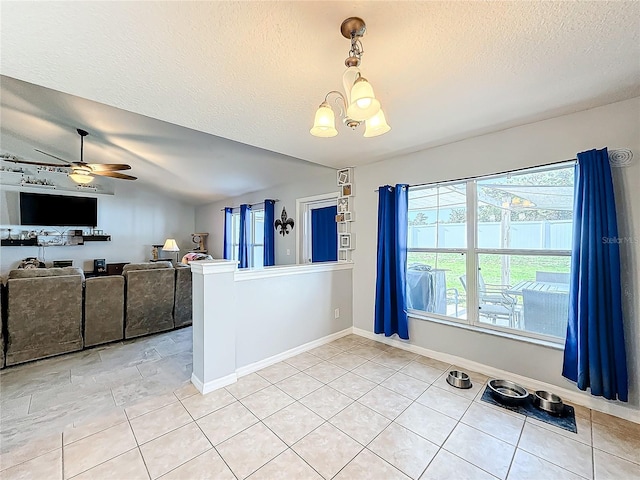 empty room featuring tile patterned floors, ceiling fan with notable chandelier, and a textured ceiling