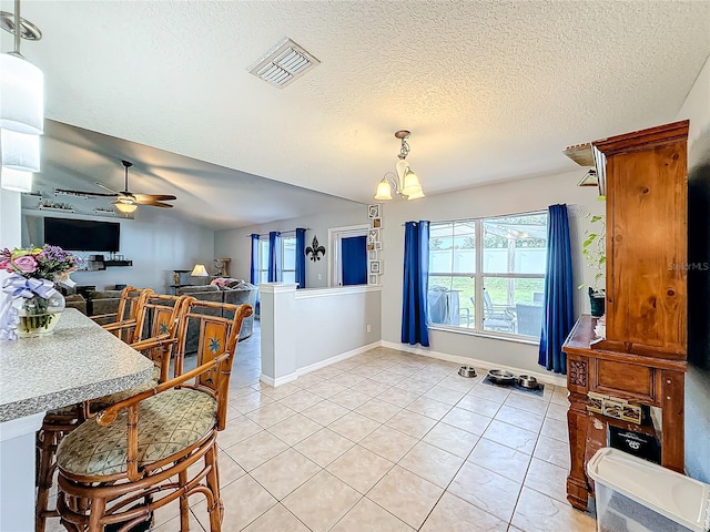 dining area featuring a textured ceiling, ceiling fan with notable chandelier, and light tile patterned flooring